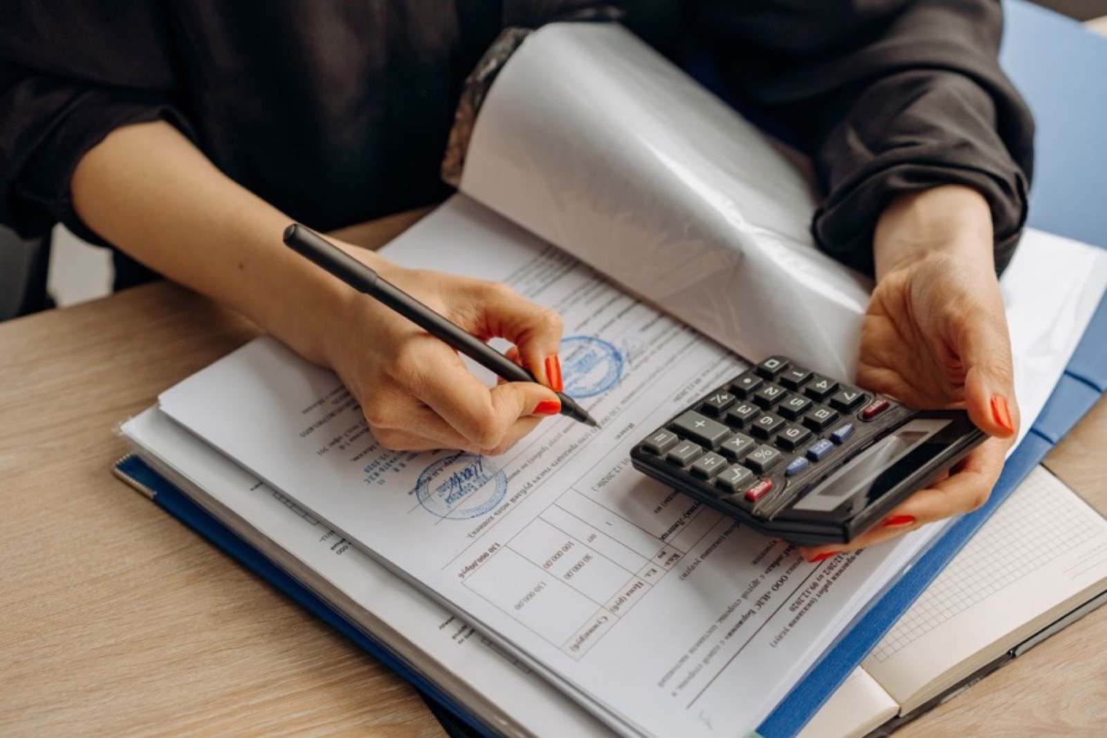 Open ledger, calculator, invoices and a green stamp